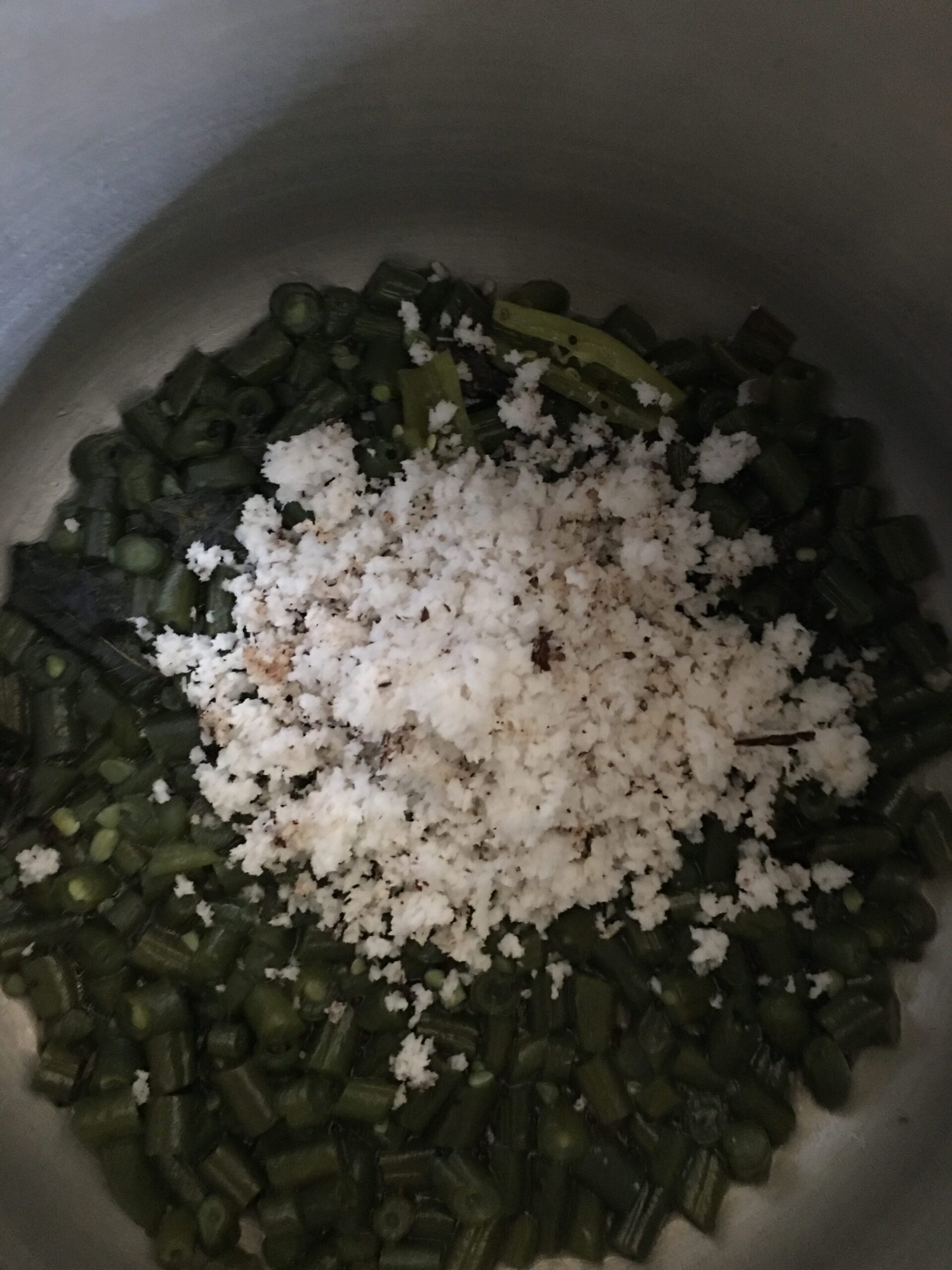 Adding freshly grated coconut to val papdichi bhaji