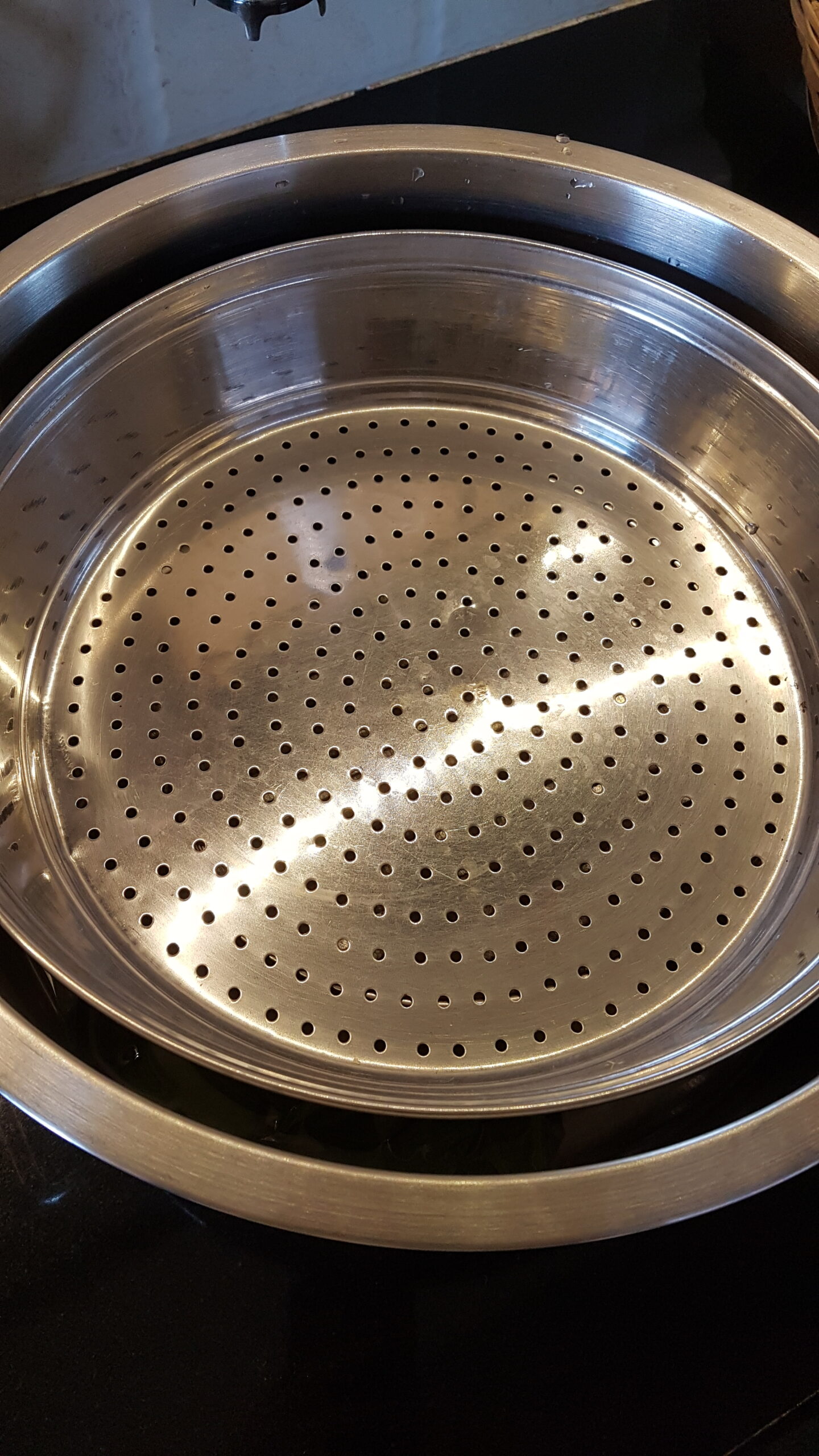Placing a perforated plate/sieve in the steamer for patoli recipe