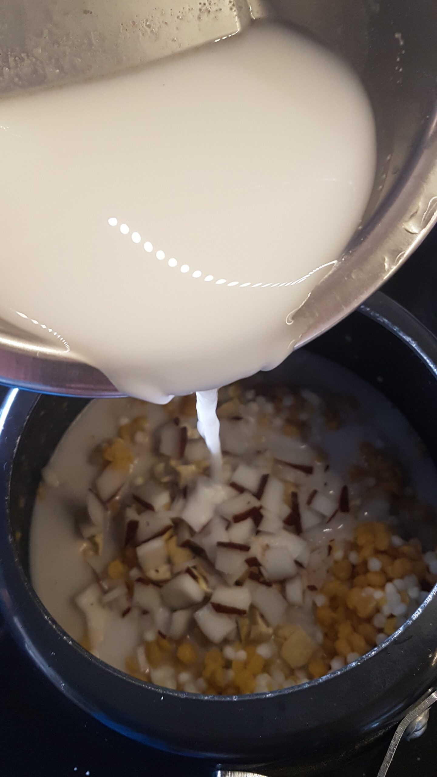 Adding thin coconut milk to cooked dal
