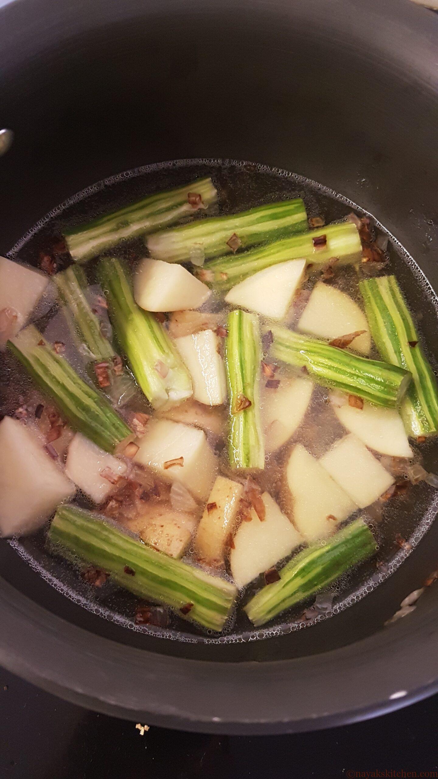 Adding water to cook drumsticks and potatoes