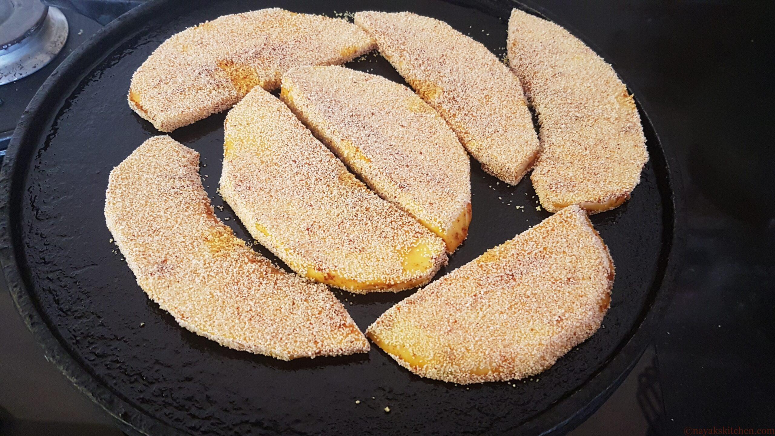 Placing rava coated breadfruit pieces on griddle
