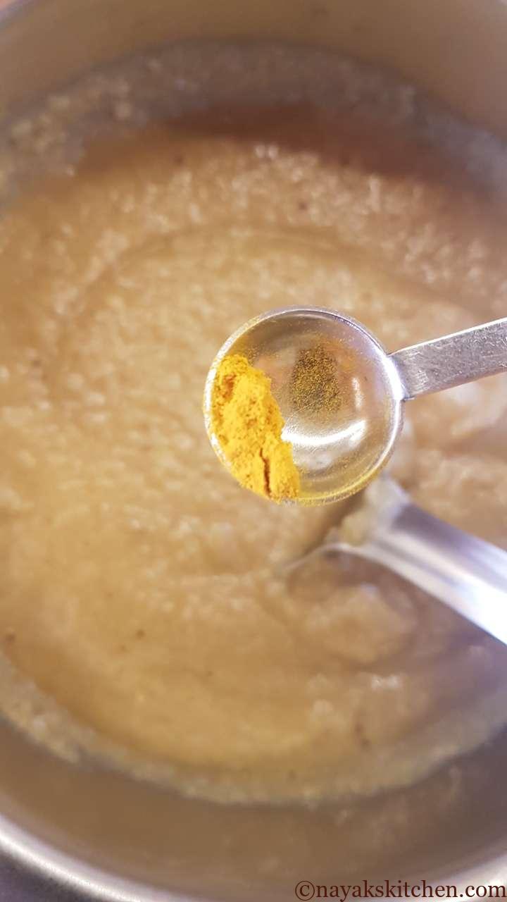 Adding turmeric powder to jackfruit idli batter
