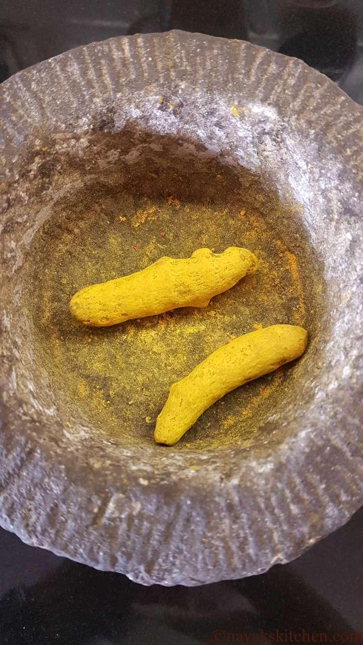 Dried turmeric roots in a mortar and pestle.