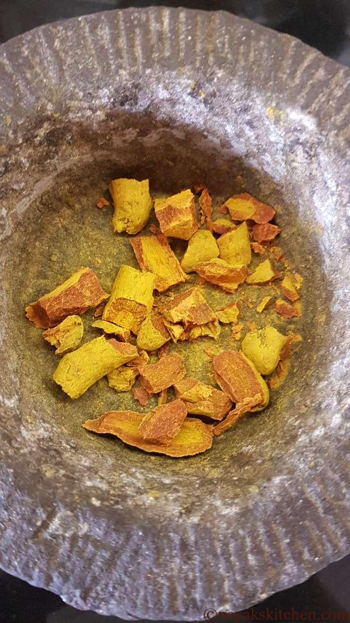 Crushed dried turmeric roots in a mortar and pestle.