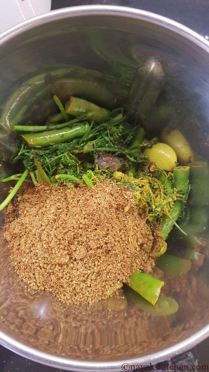 Adding spice powder and green masala ingredients to mixie jar.