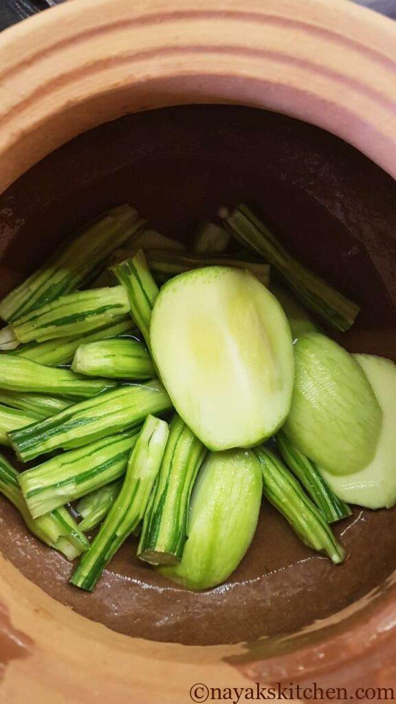 Cooking drumsticks and raw mango for goan prawns curry